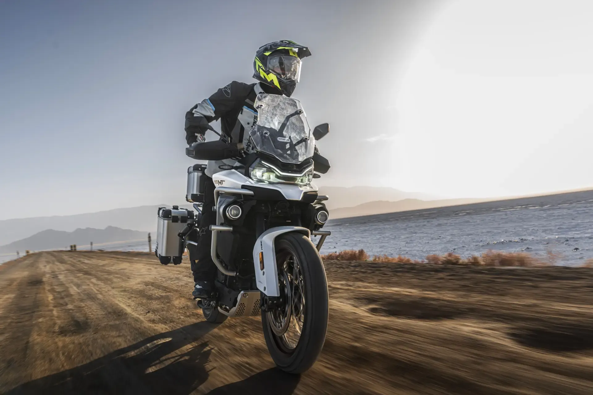 CFMoto 800MT-ES on a dirt road near water at sunset
